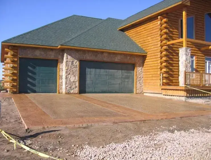 Colored concrete driveway with stamped border bands at a log home