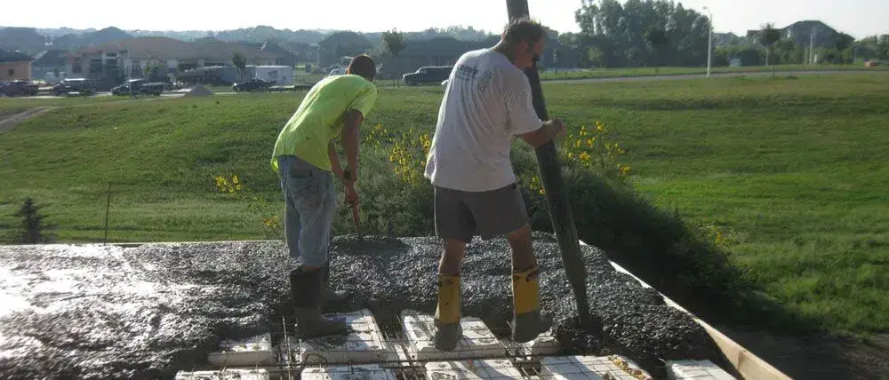 Crew pouring a concrete slab over rebar and foam insulation